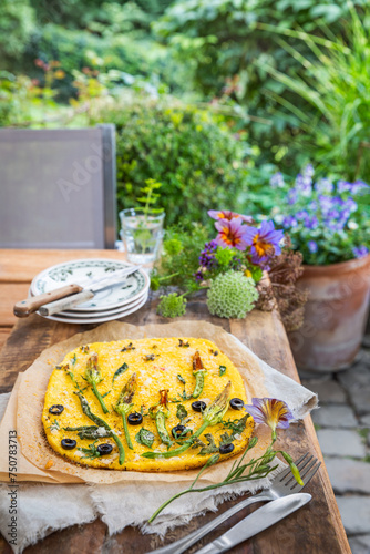 Włoska zapiekanka z polenty podana na drewnianym stole w ogrodzie.