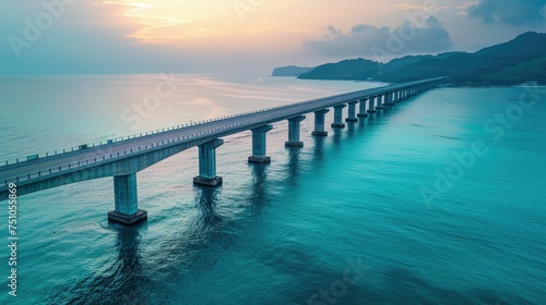 Aerial view of a long bridge crossing a tranquil blue sea at dawn
