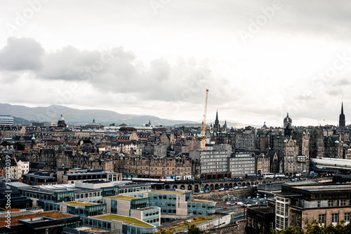 Dense panoply of buildings stretching down to horizon with a cloudy sky in the background.