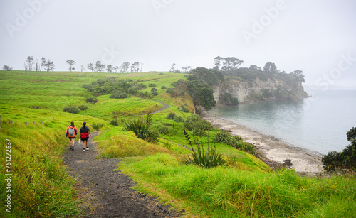 Two women hiking the Long Bay coastal Okura Track in the rain. Auckland.