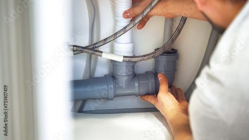 Close up plumber hands repair plumbing pipes in kitchen sink. Removing blockage clog in drain pipe. Replacement of plumbing pipes