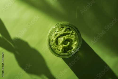 Avocado pasta, guacamole sauce on a green table next to cut avocado and spices