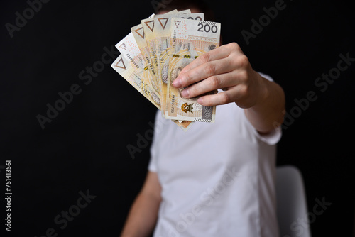 Mezczyzna trzymajacy polskie banknoty, gotowka. Zaslonieta twarz.