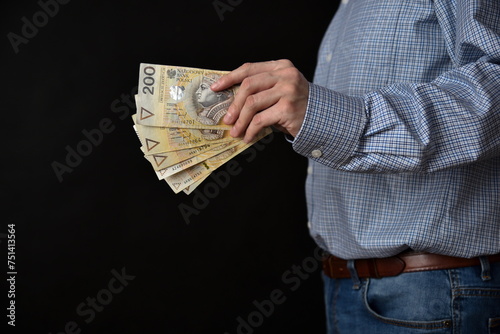 Mezczyzna trzymajacy polskie banknoty, gotowka. Plik banknotow 200 zlotych.