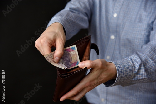 Mezczyzna trzymajacy polskie banknoty, gotowka w portfelu.