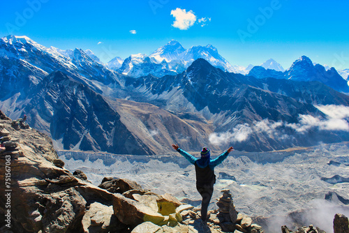 A Trekker celebrates reaching the summit of 5350 m high Gokyo Ri providing grand stand views of the Highest mountain peaks on Earth - Everest,Lhotse,Makalu, Cho Oyu and the Ngozumpa glacier in Nepal