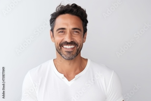 Portrait of handsome man smiling and looking at camera while standing against grey background
