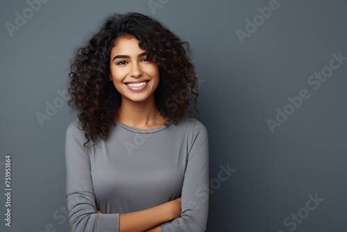 Young latin woman with pleasant smile and crossed arms.