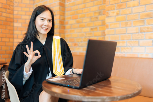 Asian female lawyer Raise hand OK symbol Wearing a legal suit, taking legal cases online via laptop for clients and defendants while waiting to mediate. Submit a complaint to the prosecutor