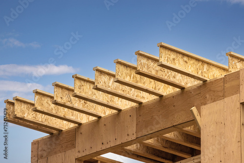 Engineered wood joists or rafters forming the roof of a house under construction