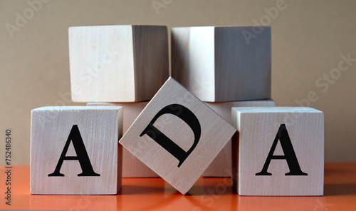 ADA - acronym on large wooden cubes on light brown background