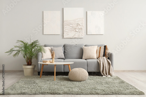 Interior of modern living room with cozy sofa, pictures and coffee table
