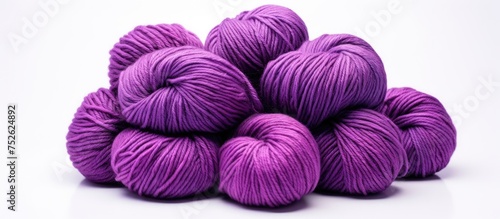 A collection of vibrant purple skeins of yarn neatly stacked on a clean white surface, ready to be used for knitting or other craft projects.
