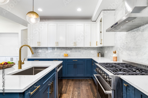 A luxurious white and blue kitchen with gold hardware, stainless steel appliances, and white marbled granite countertops. No brands or labels.
