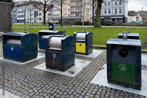 Stylish metal bins for separate waste collection standing on the sidewalk in the city.