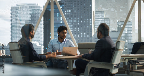 Three Young South Asian Colleagues Working in a Business Software Development Company. Indian Team Leader Using Laptop Computer, Updating Corporate Partners on Financial Market News and Trends