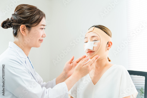 美容外科で整形手術を受けて術後に医師から診察を受ける女性 
