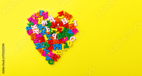 colored letters of the alphabet in the shape of a heart on a yellow background