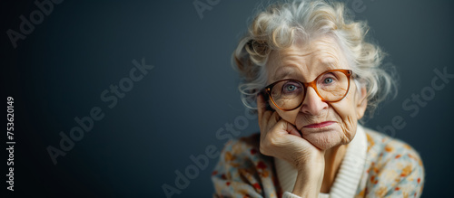 Elderly lady with glasses in deep thought.