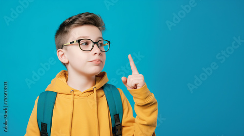 Garoto com mochila pronto para ir a escola levantando o braço isolado no fundo azul