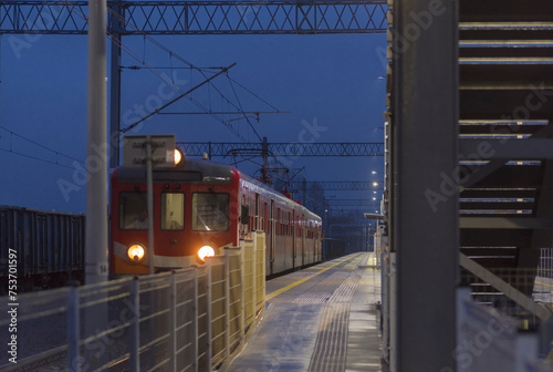 Elektryczny pociąg pasażerski na peronie dworcowym po zmroku.Oświetlony pociąg stojący na peronie w deszczowy styczniowy wieczór.