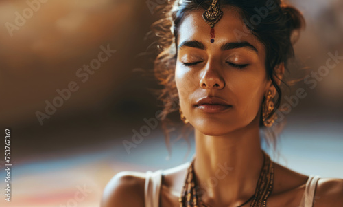 A young indian woman sits in the lotus position in a namaste position in the garden in the evening among candles, does evening relaxing yoga, takes care of her mental and physical health
