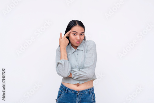 A young Asian woman makes a sarcastic gesture to her head, signaling to use your brain. Perfect for conceptual themes.