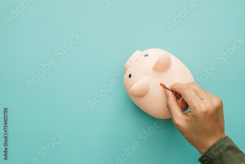 Concept for invest and saving success in the future goal. Man hand inserting coin inside of piggy bank