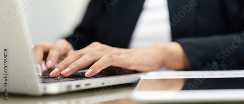 Close up of woman hands typing on laptop computer keyboard on table with sunlight 