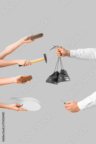 People with shoes, hammer, brushes and insoles on light background
