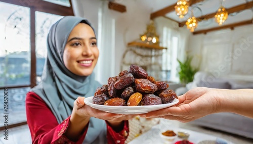 Concept Giving or Charity during Ramadhan Holy Month, Female Muslim Hand Over A Plate of Dates Fruit hurma to Other. Ifthar and Ramadan Kareem Concepts.