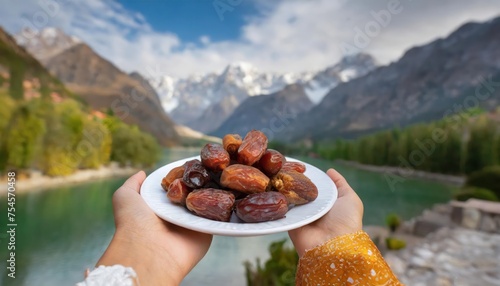 Concept Giving or Charity during Ramadhan Holy Month, Female Muslim Hand Over A Plate of Dates Fruit hurma to Other. Ifthar and Ramadan Kareem Concepts.