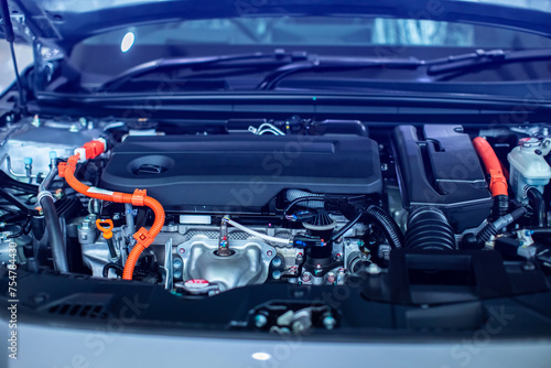 Selective focus to hybrid automotive industry part of modern new car engine room, Machine show all parts and open hood. Engine and electric motor room of new car.