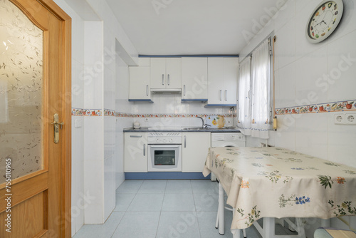 kitchen with blue and white furniture, light blue stoneware floors, table with oilcloth tablecloth and access doors to other wood and glass rooms