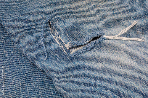 Hole torn in denim jeans. Denim clothing and work pants repair and care concept.