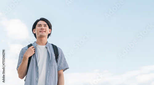 青空の下にいる笑顔の学生・大学生の男性（進学・受験・チャレンジ・希望・目標） 