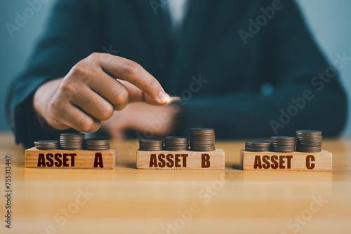 Diversify financial risk with funds. Investment asset allocation, diversification and risk management. Hand chooses on stacking coins with words ASSET A, B, C on wooden blocks. Real estate investment.