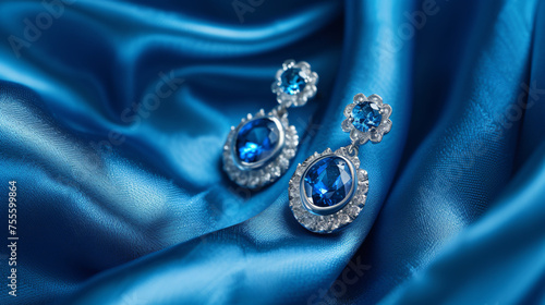 Pair of platinum earring with sapphire on blue.
