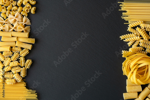 Italian Pasta variations on Black graphite board background, top view. Italian dry Pasta variation on the table. Different types of pasta on a table