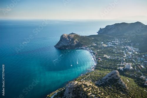 Beautiful coast of sea with rocks, town and mountains at hot summer day