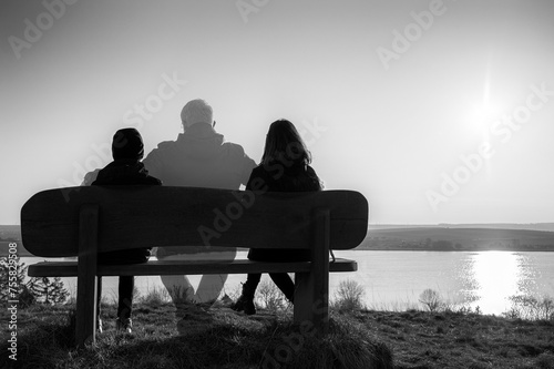 Verlust des Vaters oder Ehemanns dargestellt mit einer auf einer Bank sitzenden Familie in einer Landschaft mit See