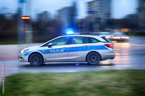 Radiowóz polskiej policji na sygnałach alarmowo szybko jedzie przez miasto na interwencję. 