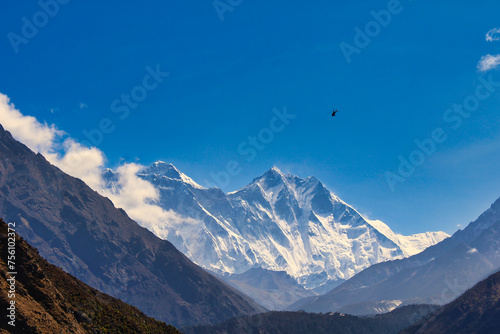 A helicopter heads to the Everest base camp and can be seen against the towering Everest and Lhotse walls from Namche Bazaar on a brilliant summer day