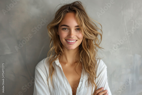 A young and fashionable woman exuding beauty and style, showing off her attractive features with a charming smile and an elegant outfit, against a simple gray background.