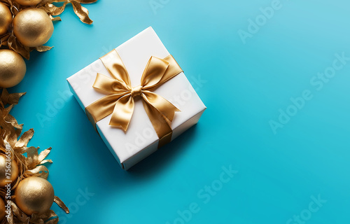 Un joli petit paquet cadeau d'anniversaire emballé avec un élégant ruban doré sur un fond bleu festif avec des décorations dorées vu de dessus