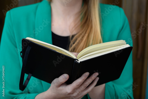 Elegenacka studentka trzyma w dłoniach otwarta książkę i czyta