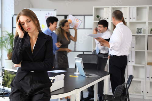 Young businesswoman suffering from noisy colleagues in office