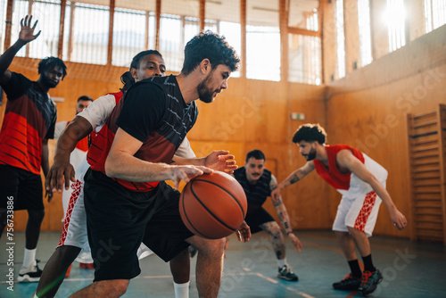 Basketball player is dribbling ball and playing on training with his team