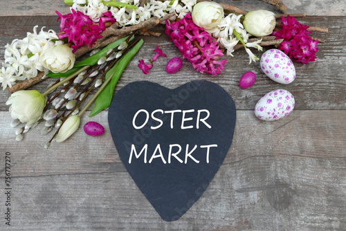 Der Text Ostermarkt auf ein Herz geschrieben mit Osterdekoration und Blumen.