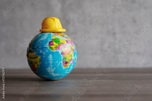 Hard hat on top of world globe. Copy space for text. Labor day, safety first concept.